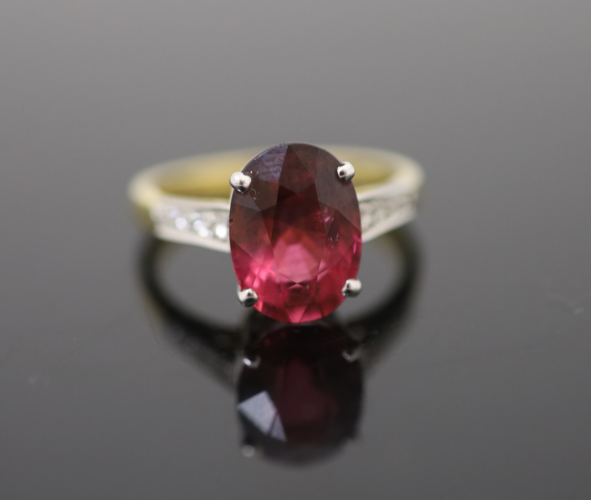 A modern 18ct gold and oval deep pink tourmaline ring, with diamond set shoulders